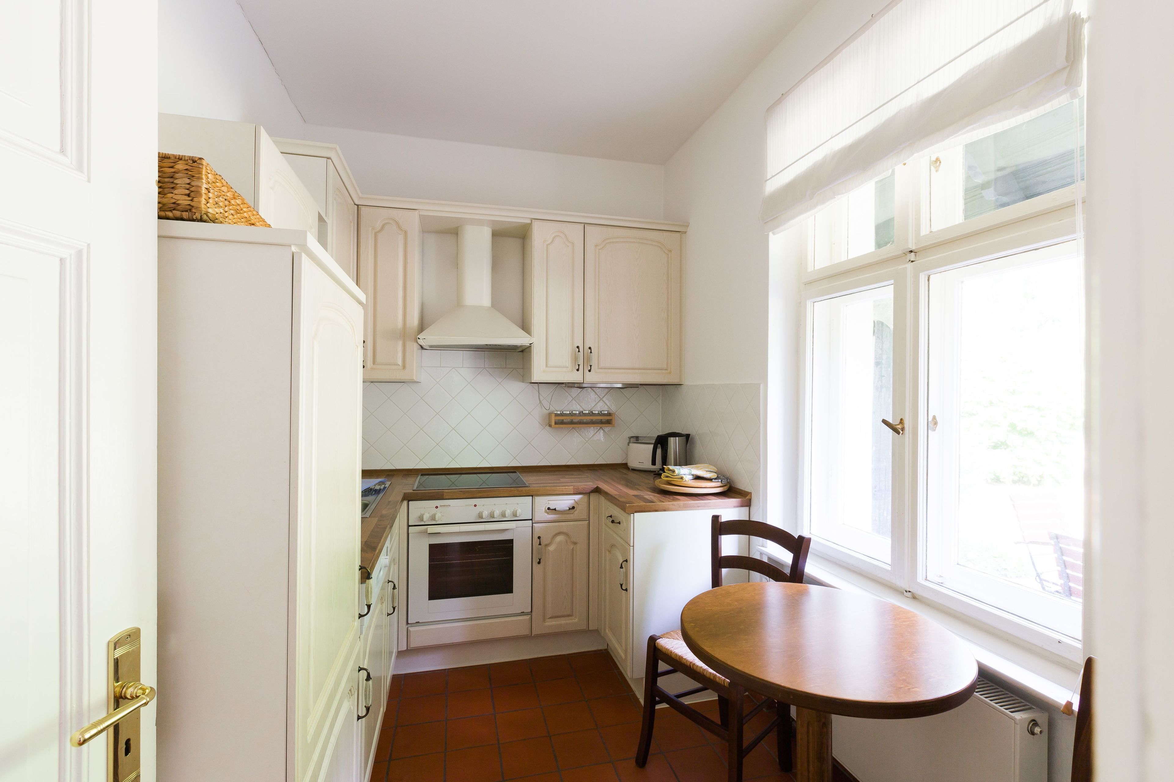 A compact kitchen with white cabinets, a stove, and a window.