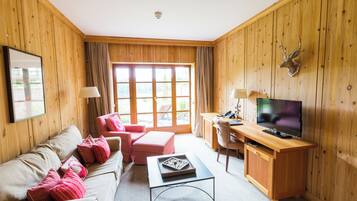 A cozy room with a wooden interior, a sofa, a TV, and a desk.