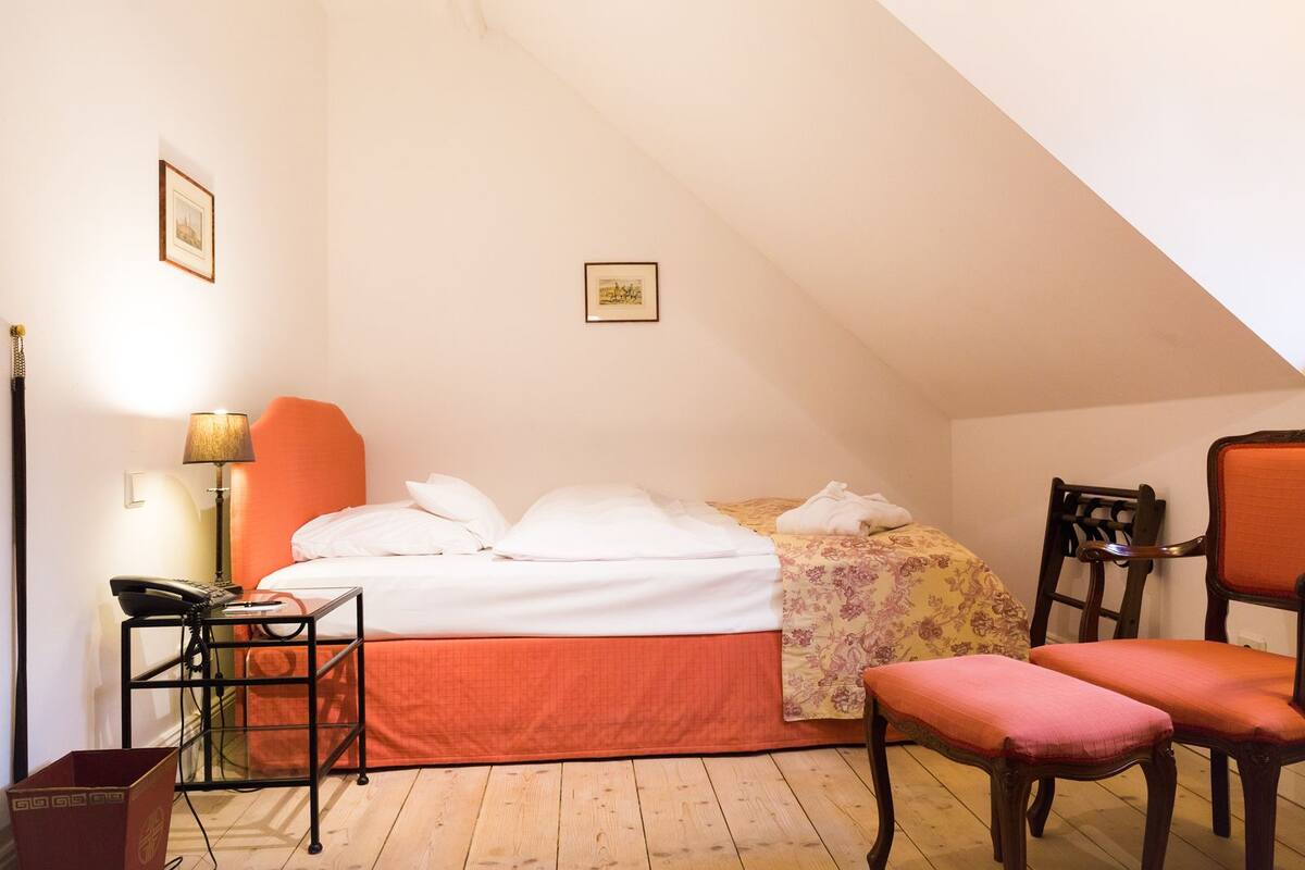 Une chambre à coucher avec un lit, une chaise, une table avec une lampe et un téléphone.