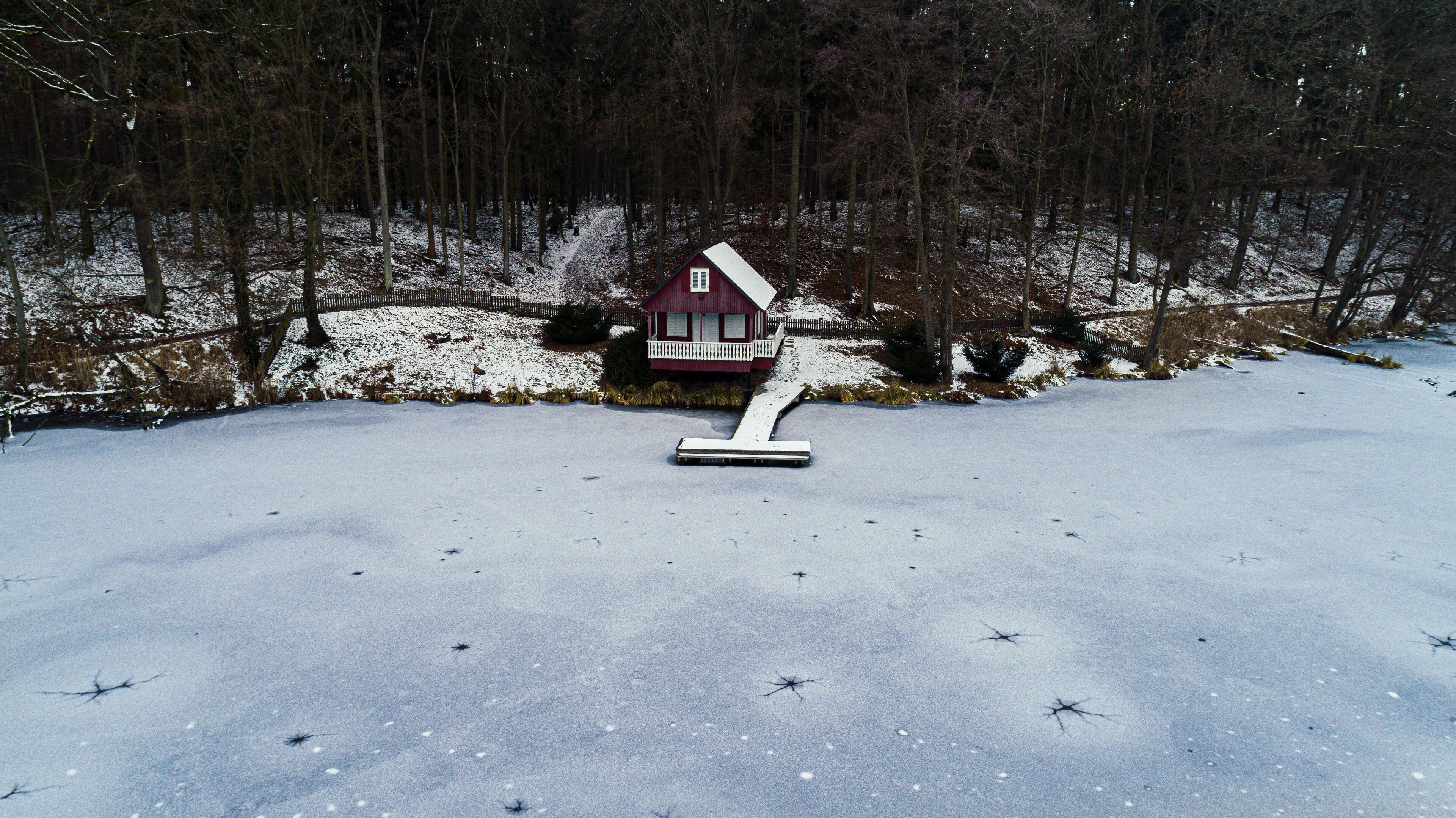 Een besneeërd landschap met een rode woning en een sneeuwschop op de voorgrond.