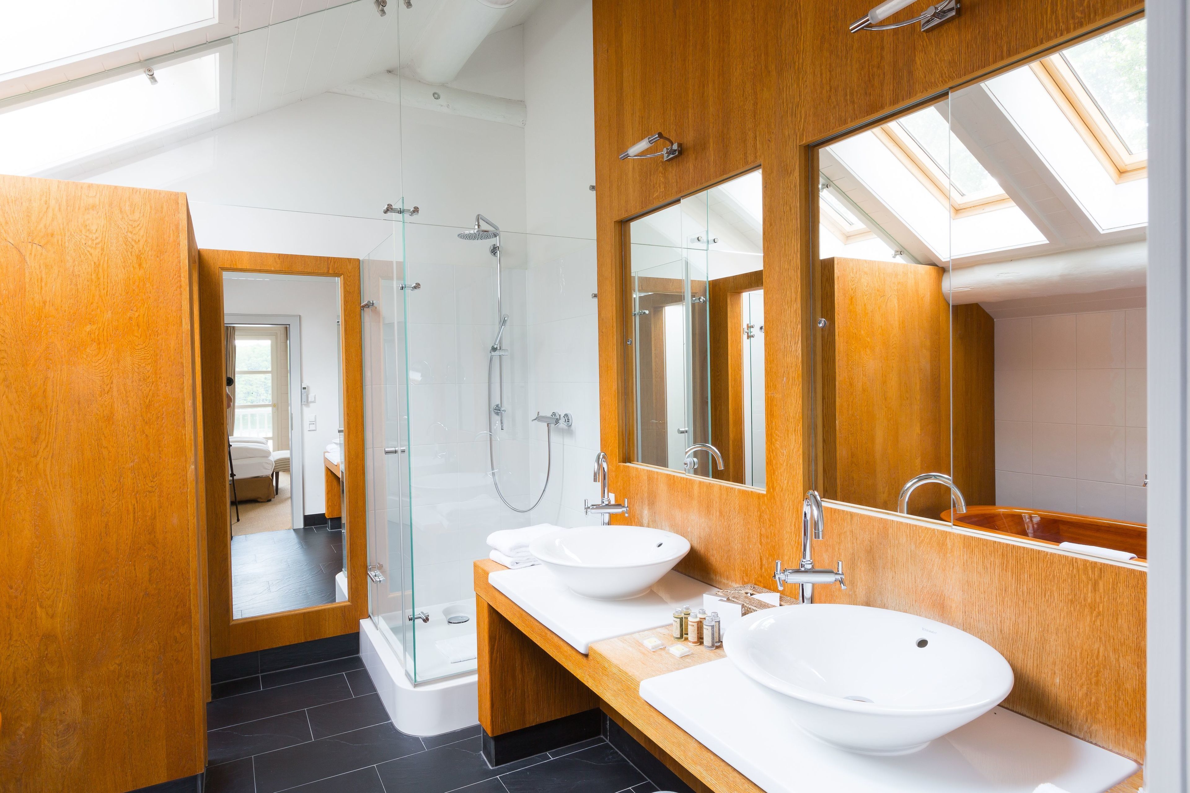 A modern bathroom with two sinks, a glass shower enclosure, and a large mirror.