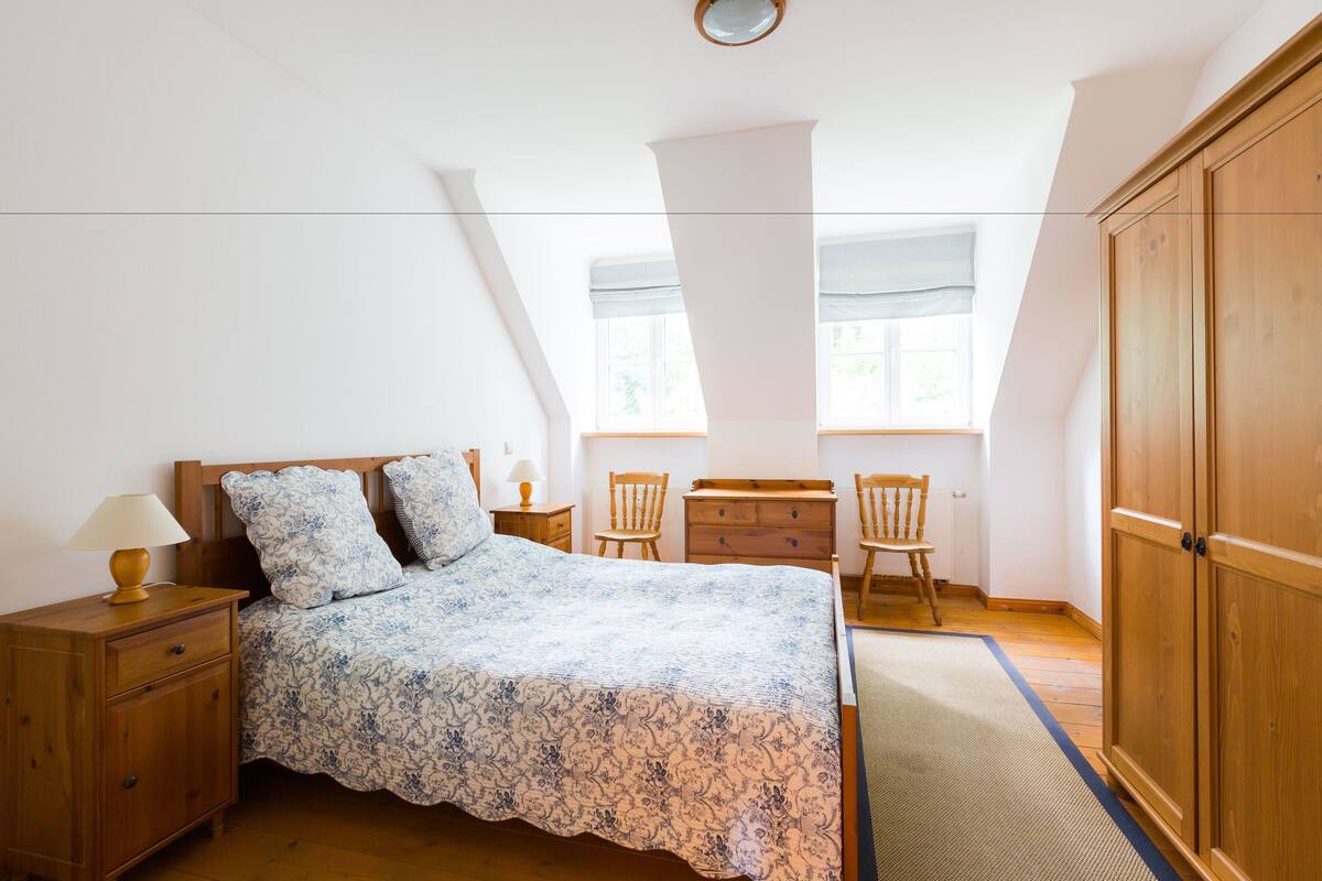 Une chambre à coucher comprenant un lit, des tables de chevet en bois, une commode et une armoire.
