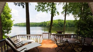 A covered patio with outdoor seating and a view of a lake surrounded by trees. - Gut Klostermühle (Briesen)