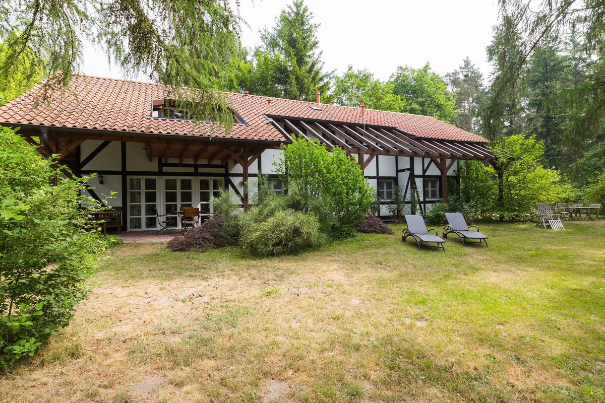 Une maison traditionnelle à colombages, dotée d’un toit en pente et d’un patio couvert.