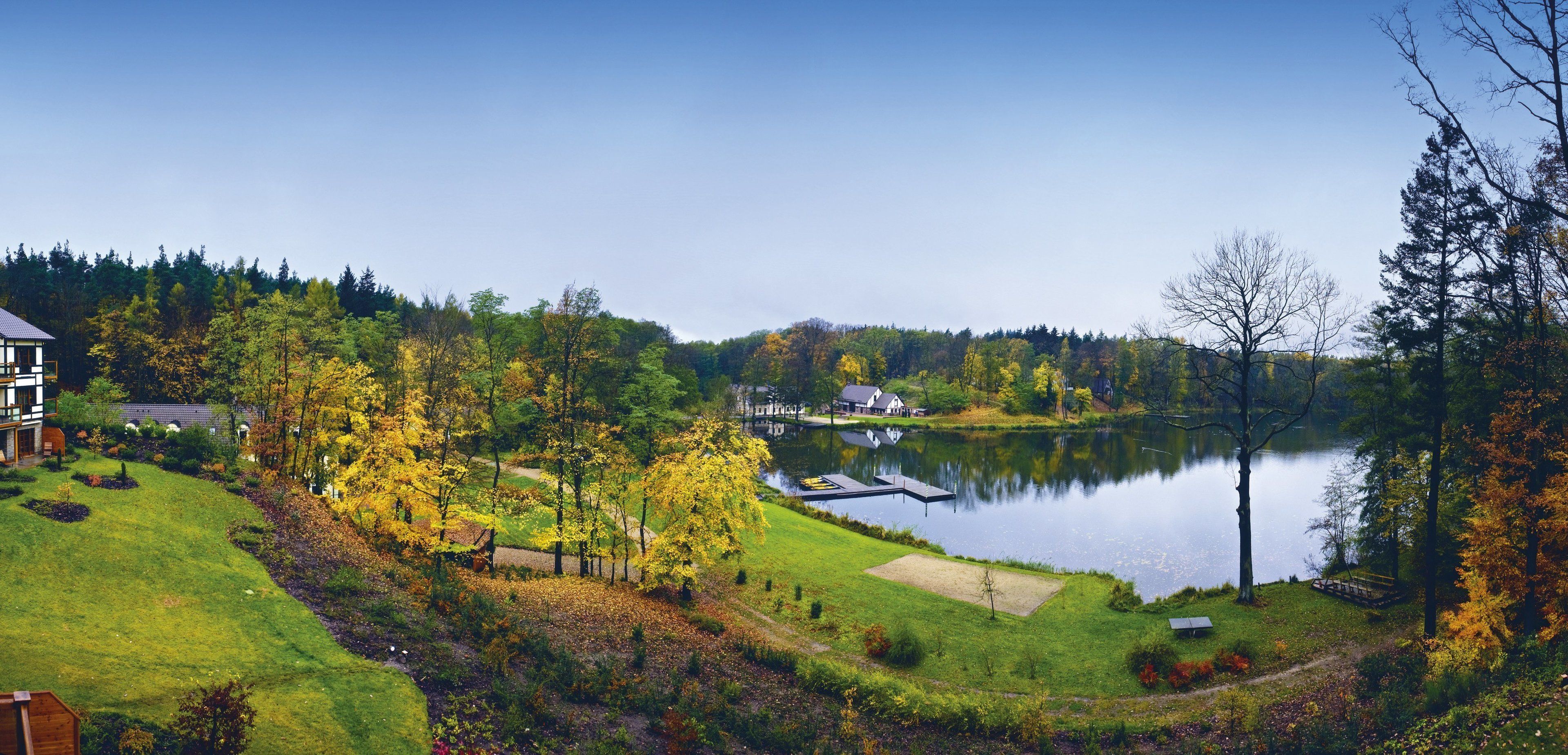 A lakeside property with a dock, a grassy area, and a building in the background.