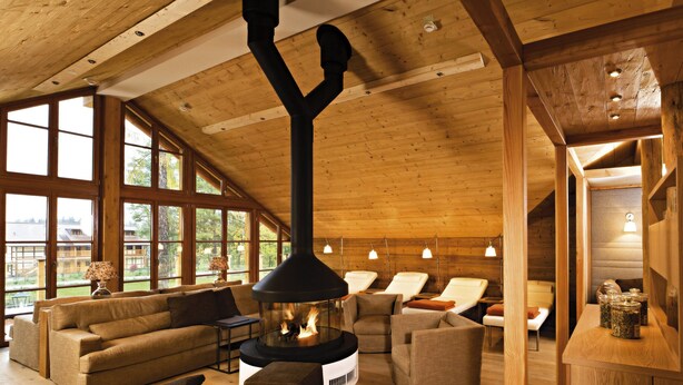 A cozy room with a fireplace, wooden furniture, and large windows. - Gut Klostermühle (Briesen)