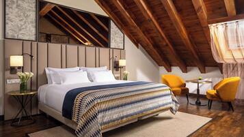 Ein Schlafzimmer mit einem großen Bett, zwei Nachttischlampen, einem kleinen runden Tisch mit einer Vase und zwei gelben Stühlen.