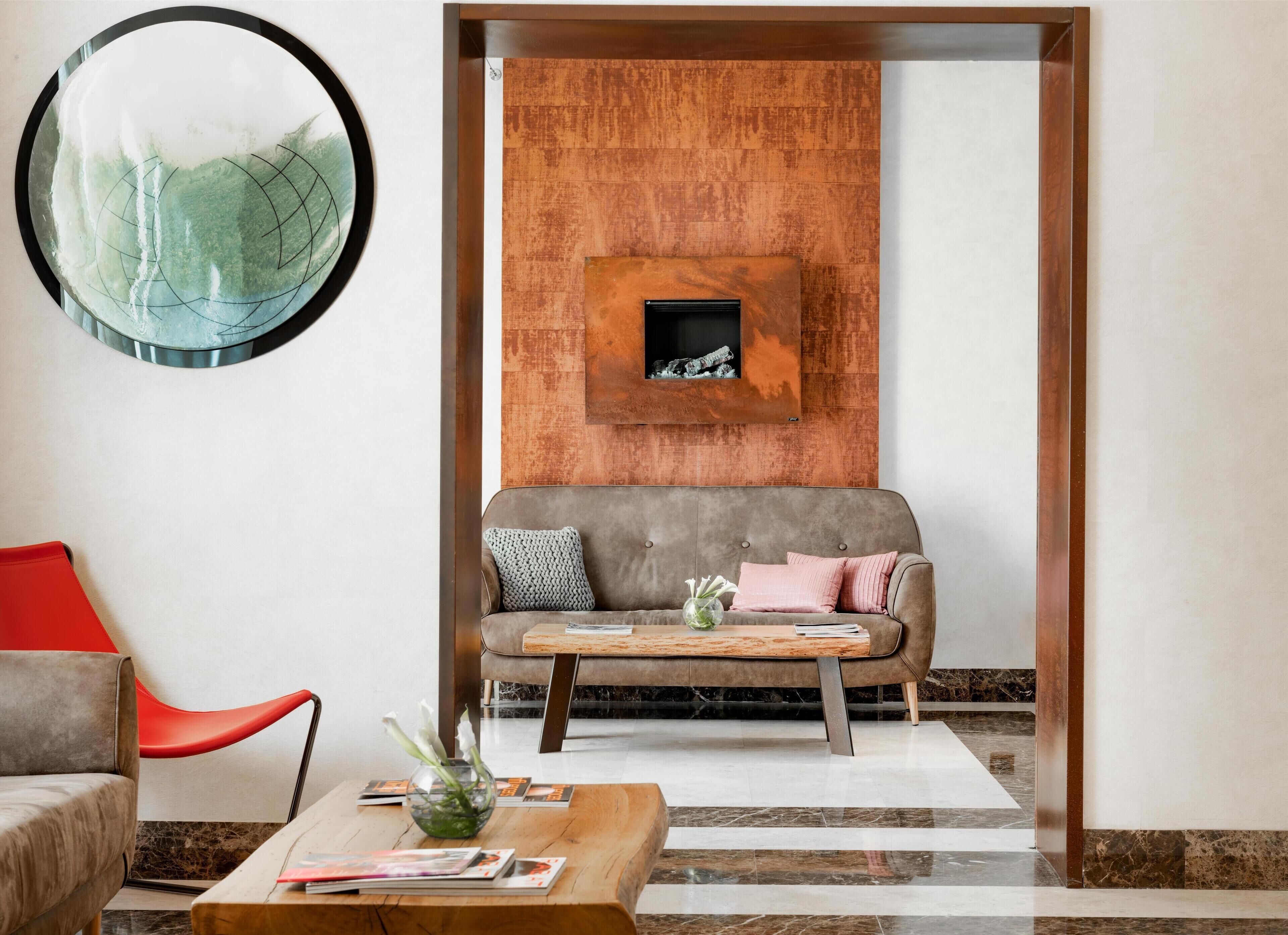 Ein modernes Wohnzimmer mit einem grauen Sofa, einem roten Sessel und einem Couchtisch aus Holz mit Zeitschriften.