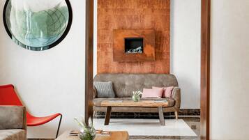 Ein modernes Wohnzimmer mit einem grauen Sofa, einem roten Sessel und einem Couchtisch aus Holz mit Zeitschriften.