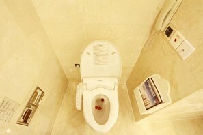 A toilet with a flush handle, a toilet paper dispenser, and a magazine on the wall. - Jinding Hotel (Wenzhou)