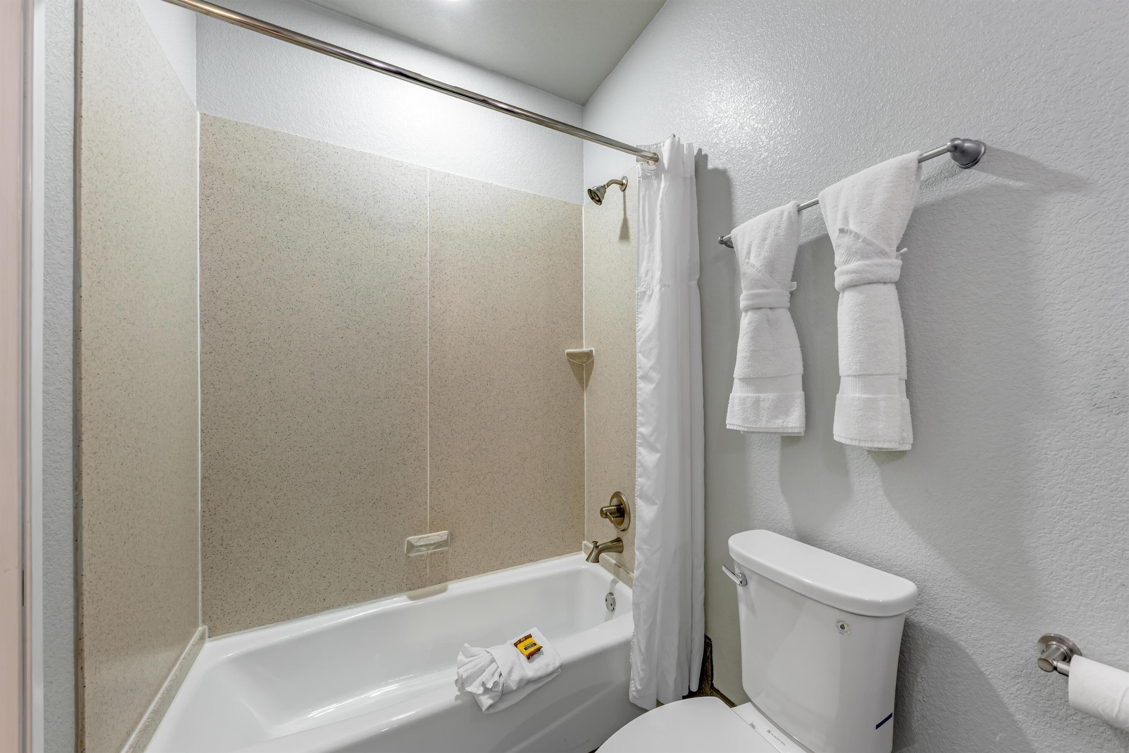 A bathroom with a bathtub, shower, toilet, and two towels hanging on the wall.