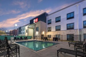 A szálloda medencetere, napozóágyakkal és egy táblával, amelyen a „Best Western Plus” szálláshelyre utalnak.