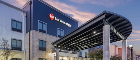 A Best Western PLUS hotel with a modern design, featuring a covered entrance and a landscaped outdoor area.