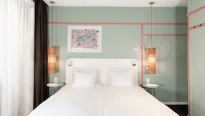 A double bed in a room with a green wall, a map, and two bedside lamps. - Conscious Hotel Vondelpark (Amsterdam)