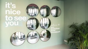 A wall with six circular mirrors and a welcoming message for Conscious Hotel Vondelpark. - Conscious Hotel Vondelpark (Amsterdam)