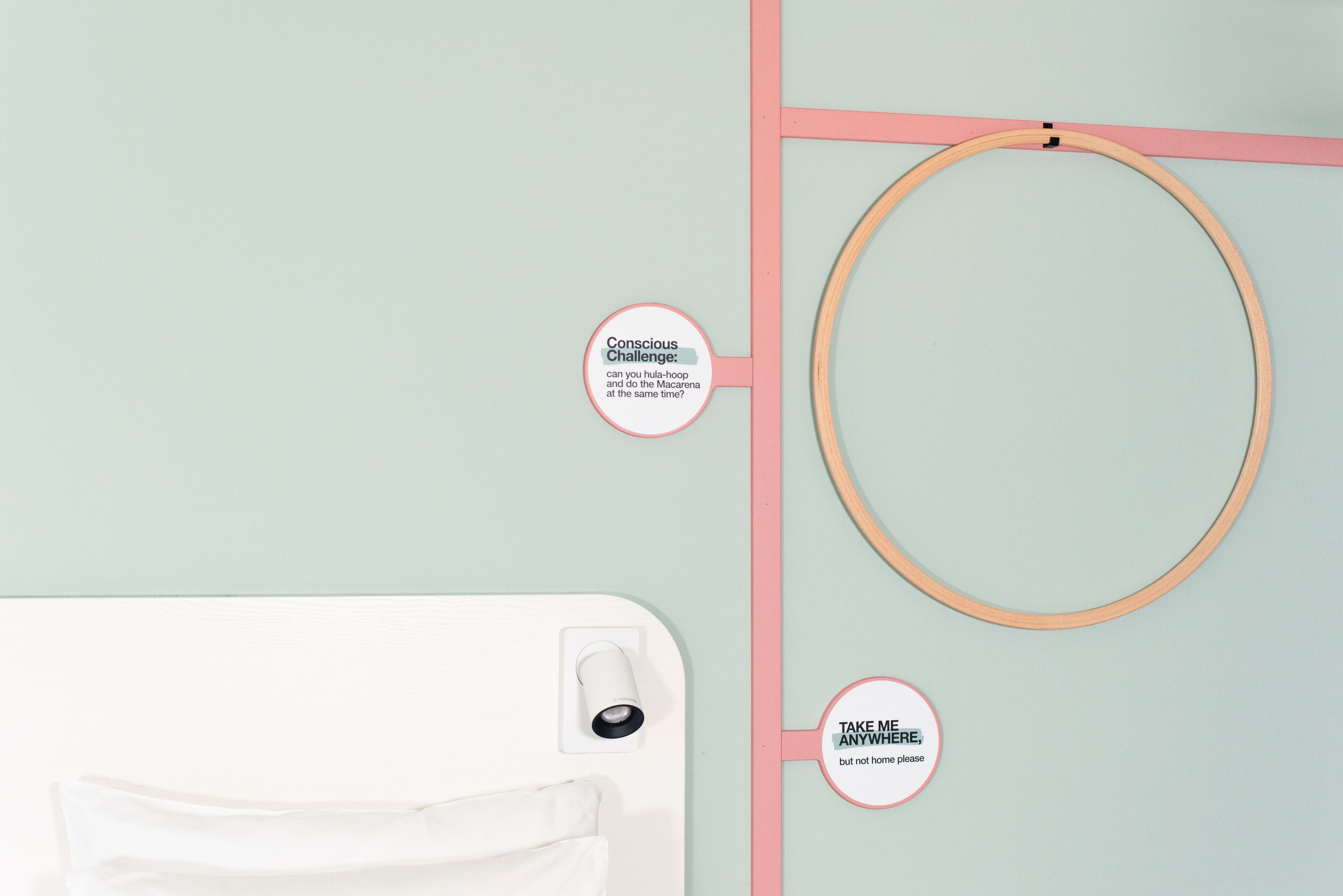 A room with a bed, a wooden hoop, and a wall-mounted light fixture.
