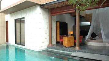 A modern outdoor pool area with a seating area, a covered section with a canopy, and a large sliding door.