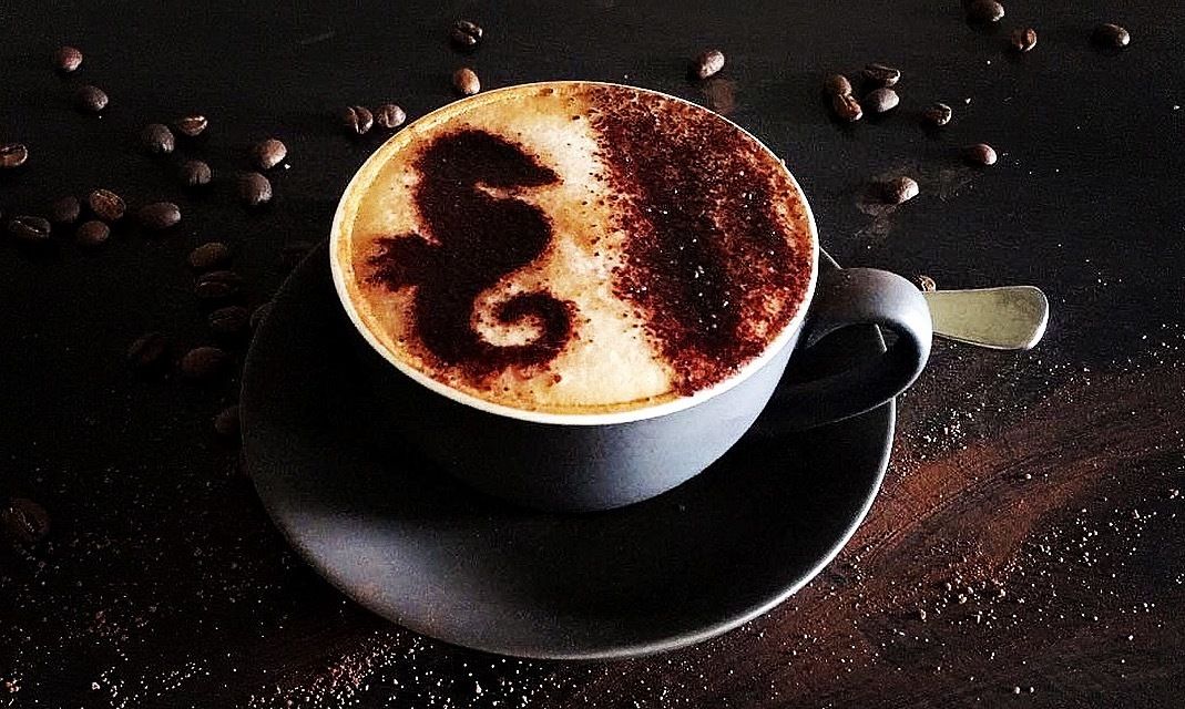 A cup of coffee with a latte art design on a saucer.