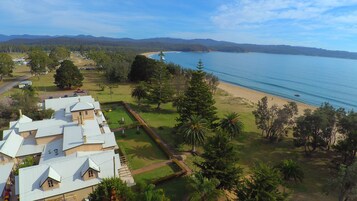 Vista aérea de una propiedad costera con playa, campo de golf y un edificio grande con varios tejados.