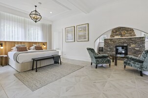 Un dormitorio con una cama grande, una chimenea de piedra y dos sillones.