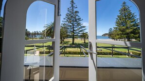 A view from a room with large windows overlooking a park with trees and a body of water. - Seahorse Inn Hotel & Villas (Boydtown)