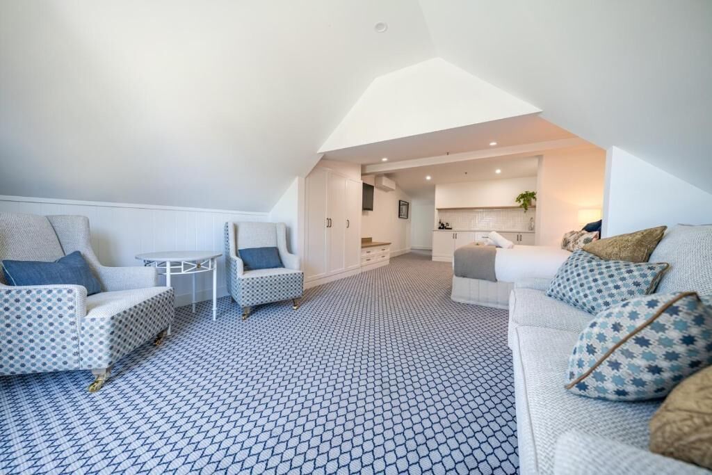 A modern loft apartment with a high ceiling, a kitchen area, and a living room with patterned flooring.