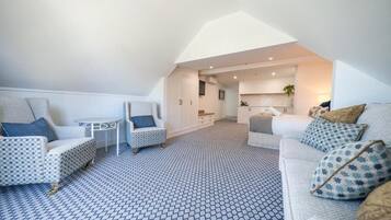 A modern loft apartment with a high ceiling, a kitchen area, and a living room with patterned flooring.