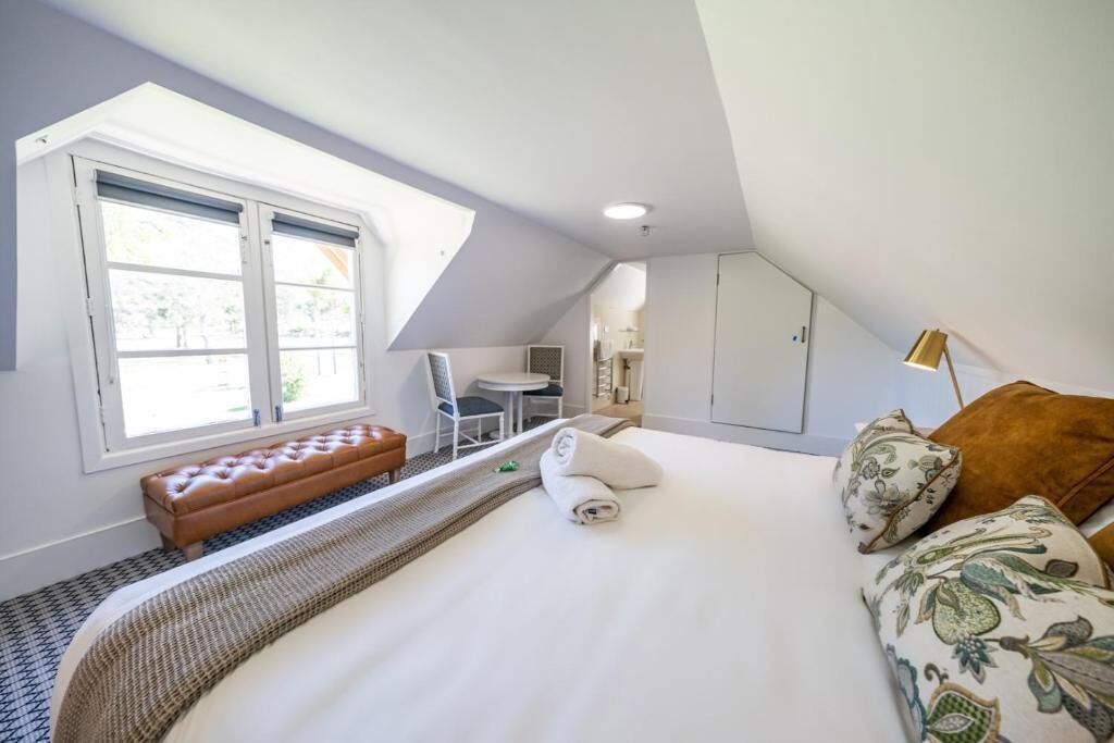 Ein Schlafzimmer mit einem großen Bett, einer Bank, einem Schreibtisch und einem Stuhl.