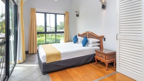 A bedroom with a bed, a nightstand, a ceiling fan, and a window with curtains. - Dreamcatcher Beachsides Apartments (Port Douglas)