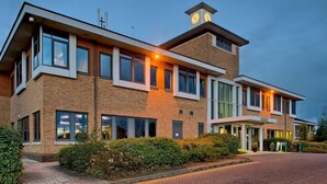 Un bâtiment moderne doté d’une tour horlogée, de grandes fenêtres et d’une façade en briques.