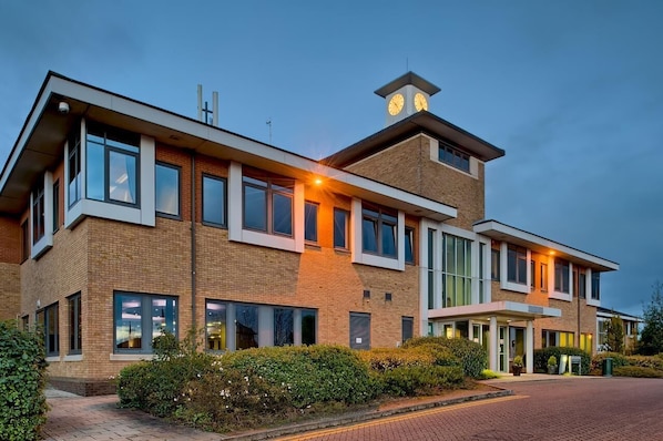 Un bâtiment moderne doté d’une tour horlogée, de grandes fenêtres et d’une façade en briques.