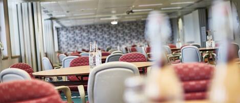 A conference room with tables and chairs, a projector, and a patterned wall.