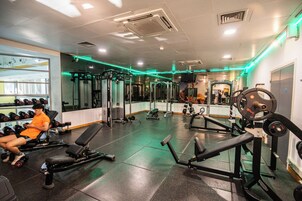 Un gimnasio con equipo de levantamiento de pesas, bancos y un espejo.
