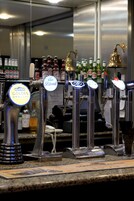 Zona de bar con múltiples grifos de cerveza, cada uno etiquetado con una marca diferente.
