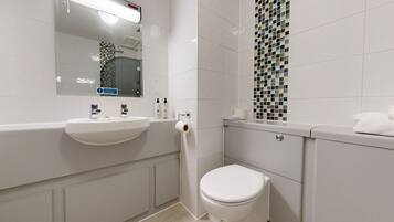 A modern bathroom with a white sink, mirror, and toilet.