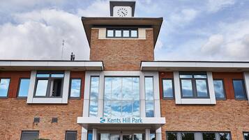 Un edificio con una torre de reloj, un cartel que dice "Kents Hill Park" y ventanas grandes.