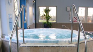 Un jacuzzi avec des marches menant à l’intérieur, une horloge au mur et un panneau indiquant « Il est interdit de plonger ».