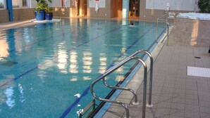 Une piscine intérieure à l’eau claire, avec des couloirs délimités et un panneau indiquant qu’il est interdit de plonger.