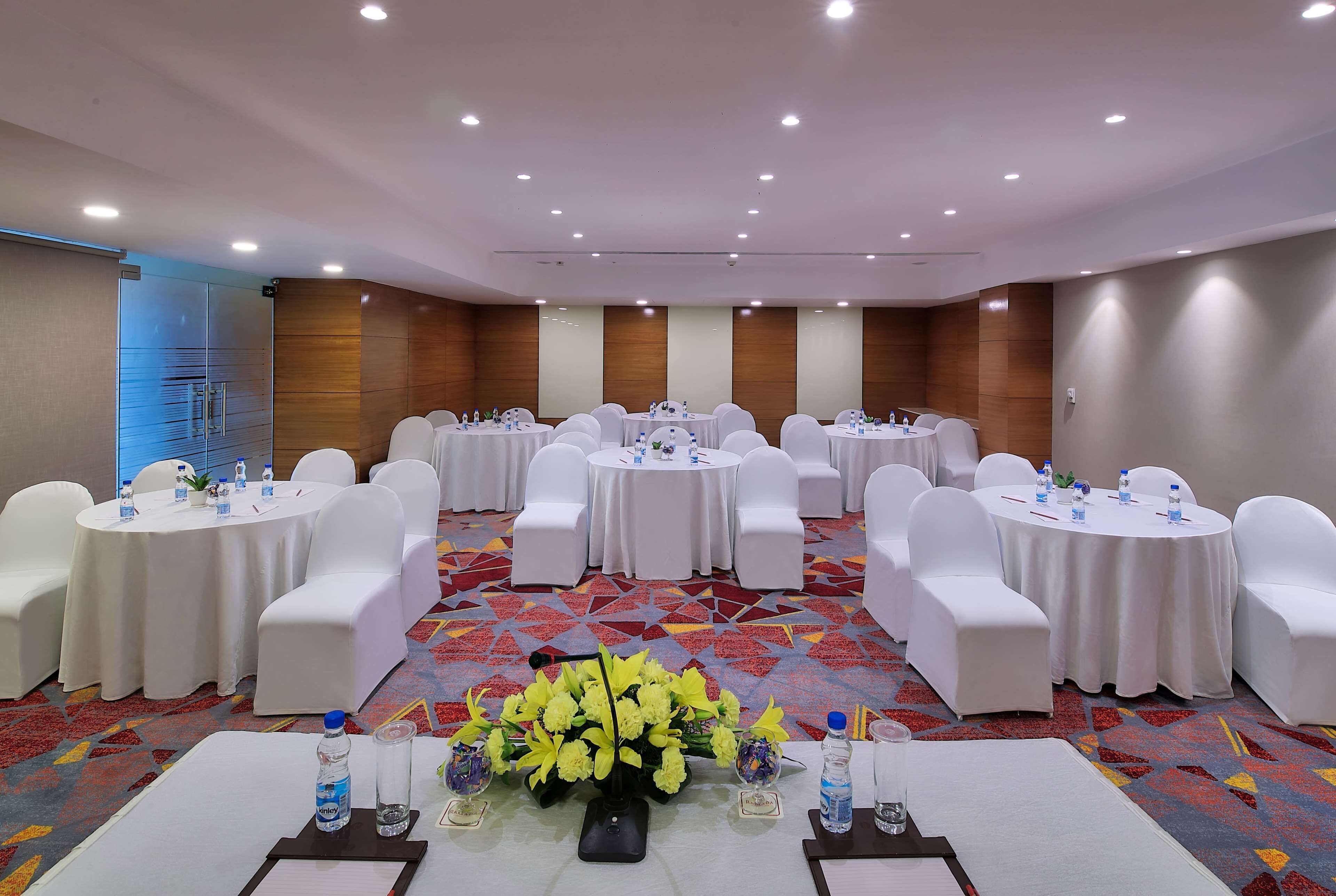 A conference room with round tables, white chairs, and floral centerpieces.