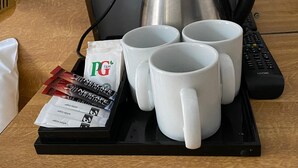 A tray with four white mugs, a black coffee pot, a remote control, and packets of PG tips and Nescafe Original coffee. - Alumhurst Hotel (Blackpool)