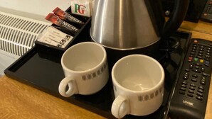 A coffee station with a coffee pot, two cups, a tray, and a remote control. - Alumhurst Hotel (Blackpool)