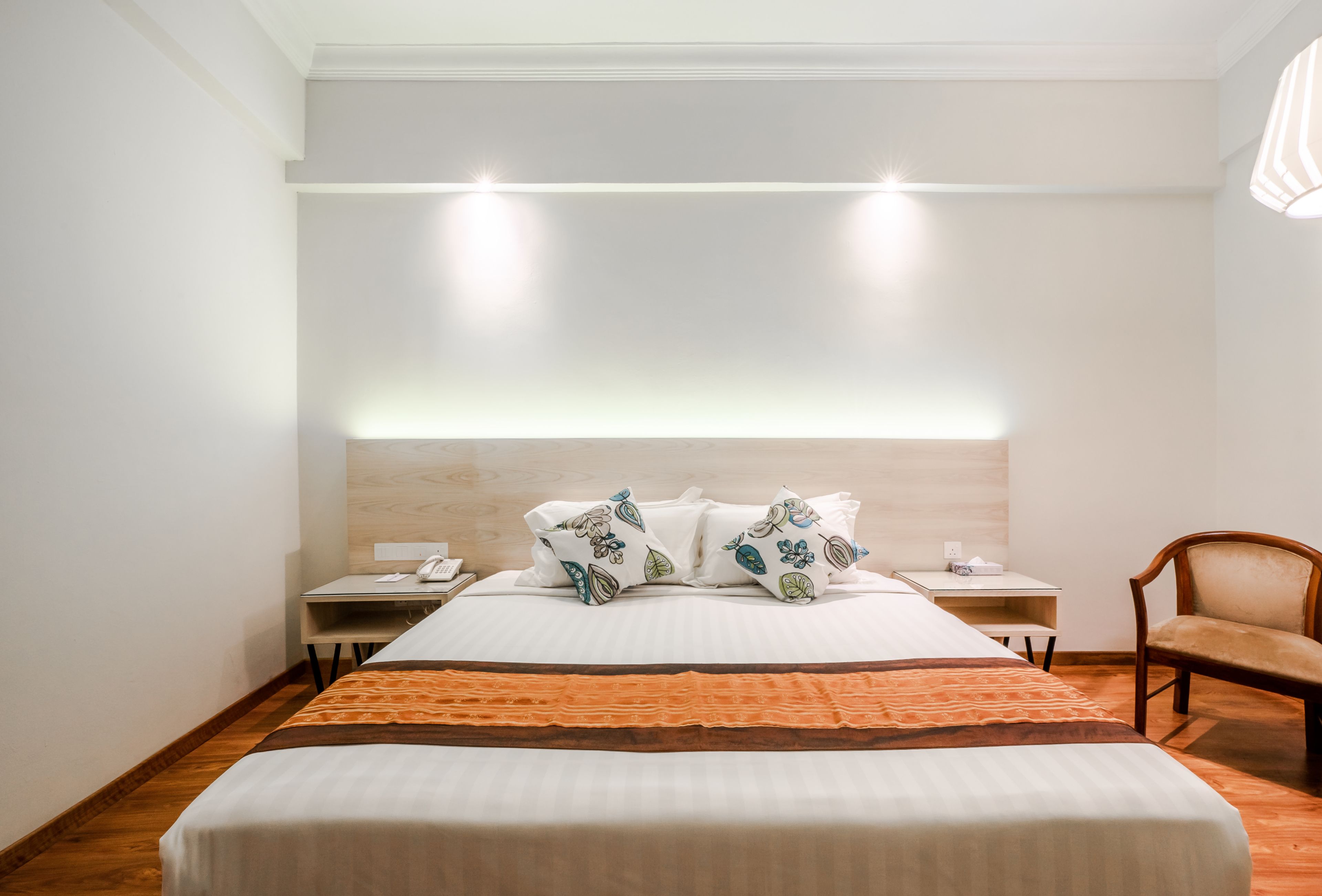 A hotel room with a large bed, a bedside table with a lamp, and a chair.
