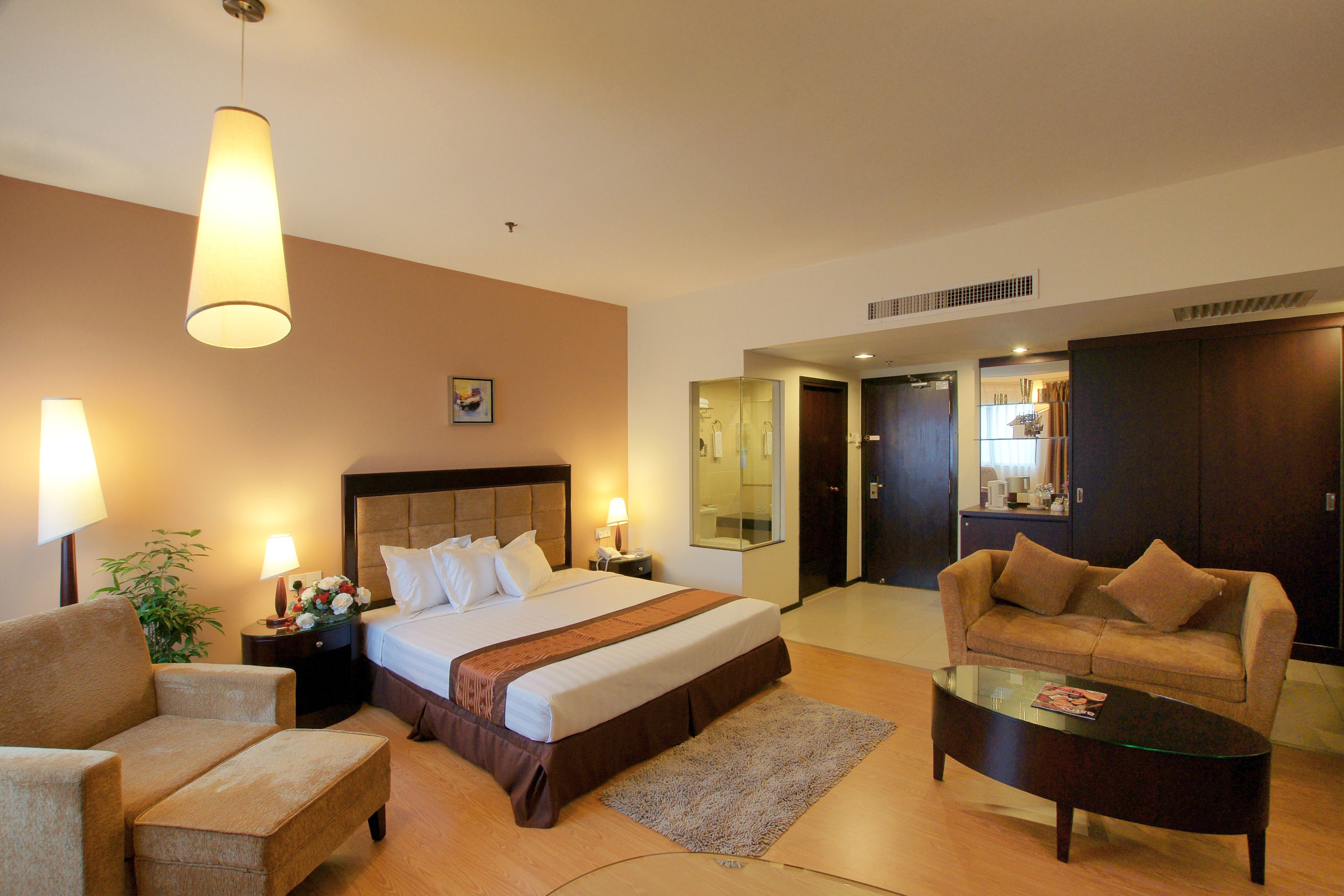 Een hotelkamer met een bed, een bank, een salontafel, een nachtkastje en een lamp.