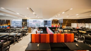 Un restaurante moderno con mesas altas, cabinas, ventanas amplias y vistas a la ciudad.