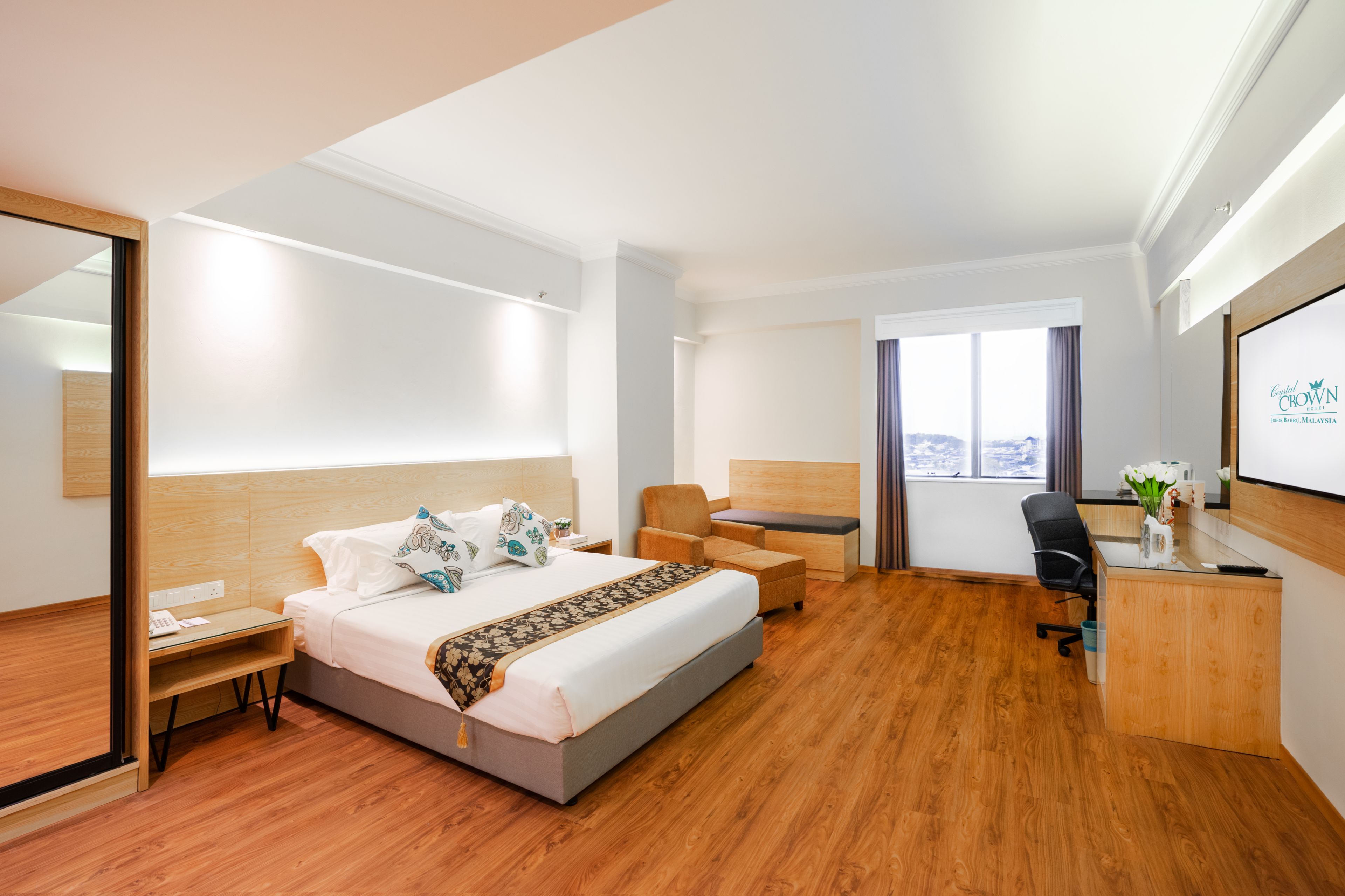 Ein modernes Hotelzimmer mit einem großen Bett, einem Schreibtisch, einem Stuhl und Blick auf die Stadt.