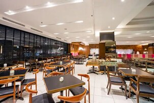 Um restaurante moderno com várias mesas e cadeiras, um grande painel de cardápio e uma área de balcão.