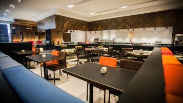 A modern restaurant with a long counter, multiple tables, and booths.