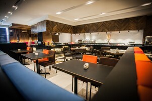 Un ristorante moderno con un lungo bancone, diversi tavoli e posti a sedere riservati.