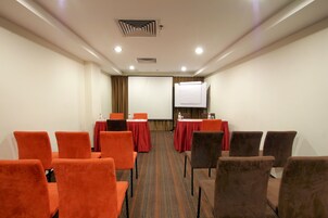 A conference room with rows of chairs, tables, and a projection screen.