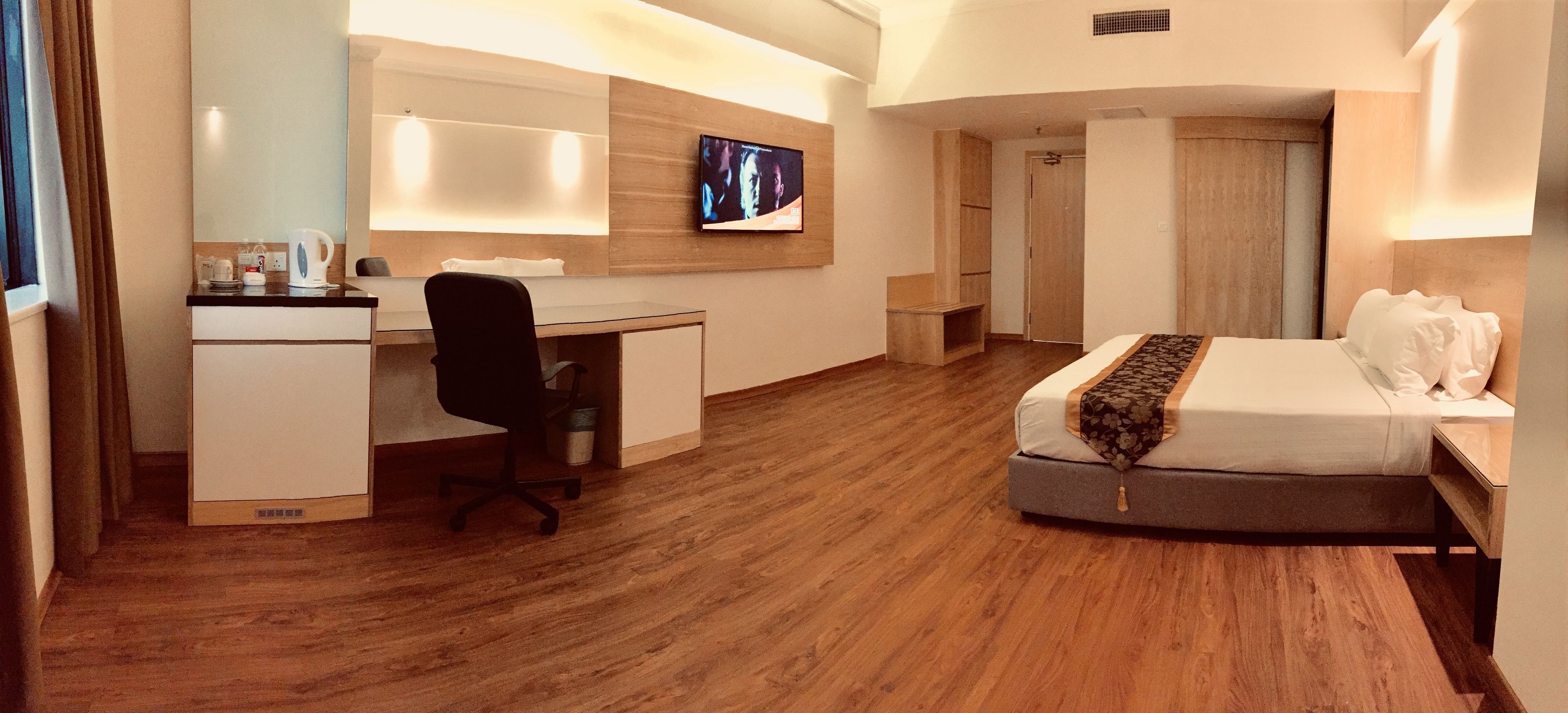 A hotel room with a bed, a desk, a chair, a TV, and a wardrobe.